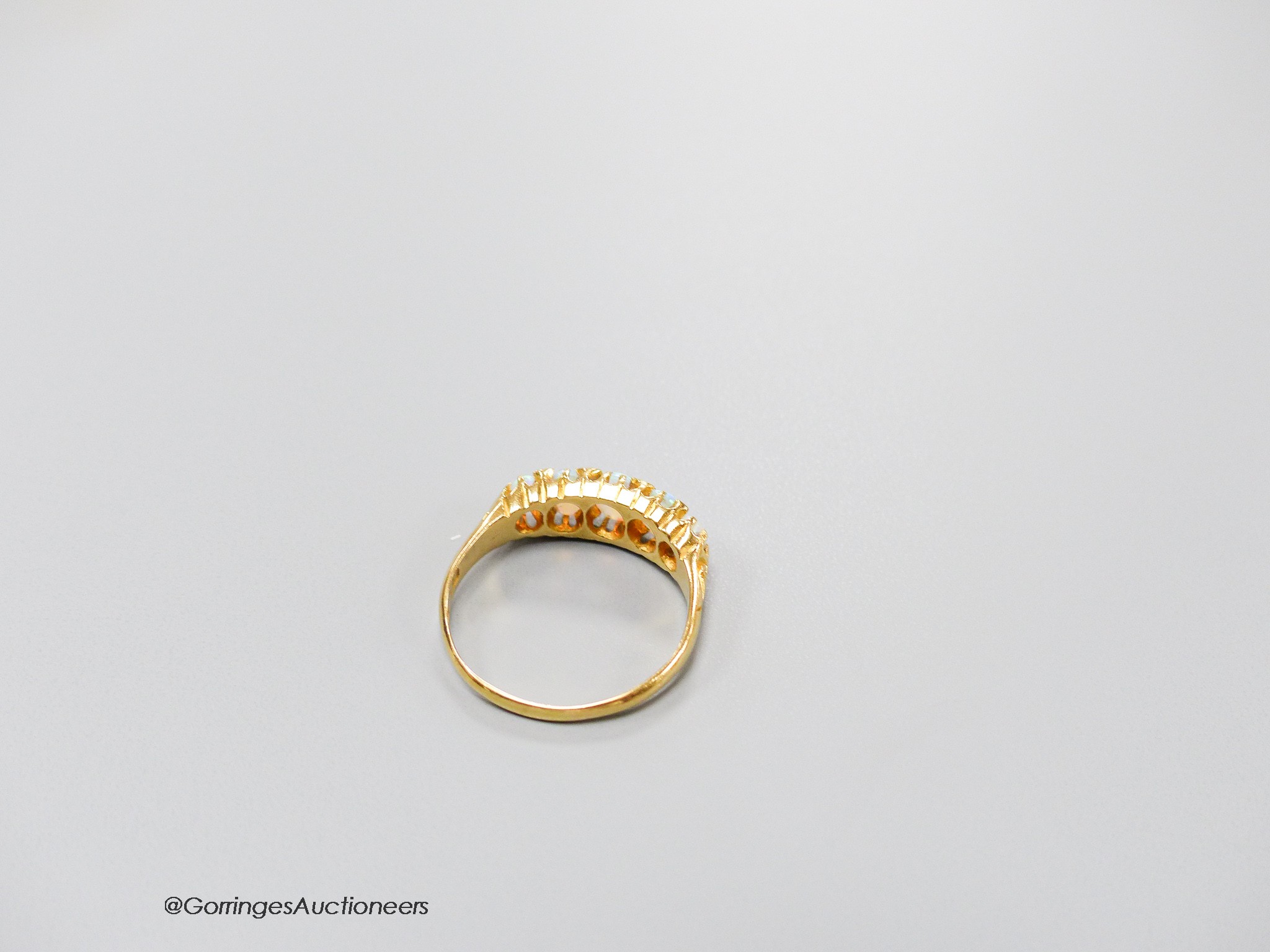 An Edwardian 18ct gold and graduated white opal set half hoop ring, with diamond chip spacers, size Q, gross 3.5 grams